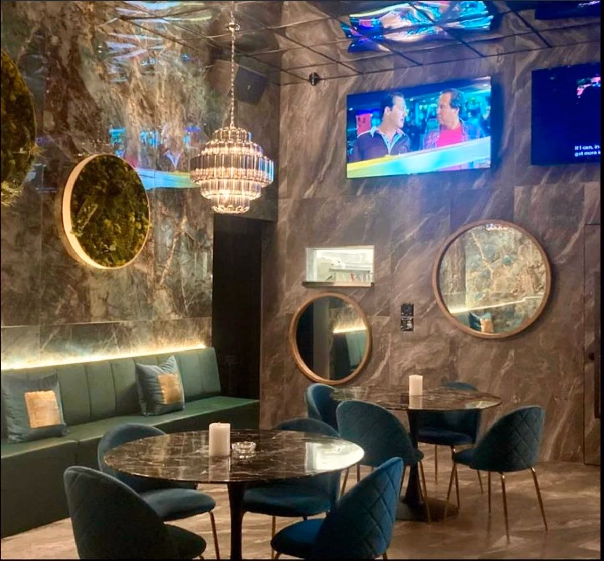 Tables, dark green chairs and pendant lights in Boardwalk’s lounge.