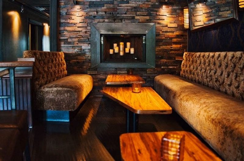 Tufted lounge seating and a fireplace inside DrYnk Bar & Lounge.