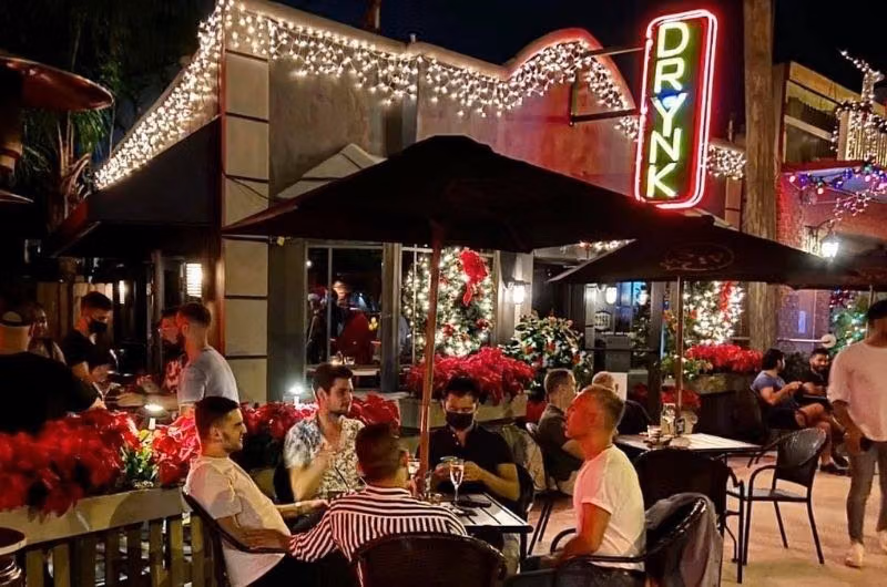 A busy evening on the DrYnk patio beneath string lights and its illuminated sign.