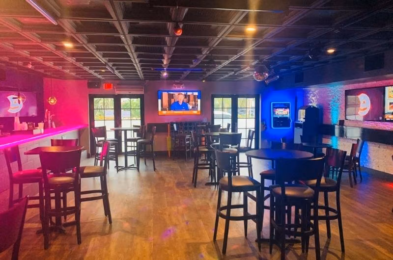 Tables, bar stools and colored lighting inside LIT Bar in Wilton Manors.