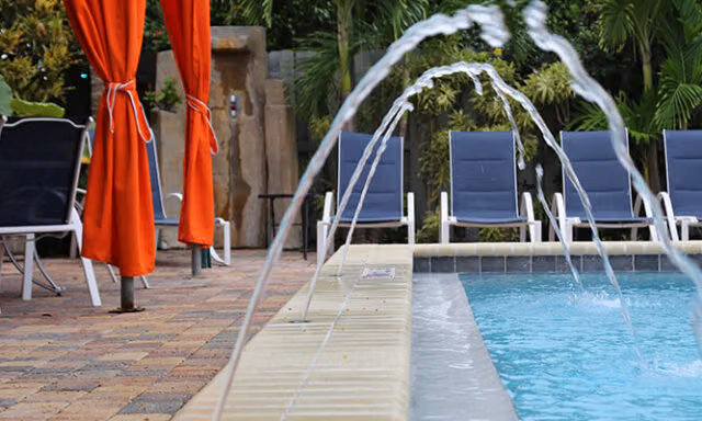 Water jets arc into a pool beside loungers at The Cabanas Guesthouse & Spa.