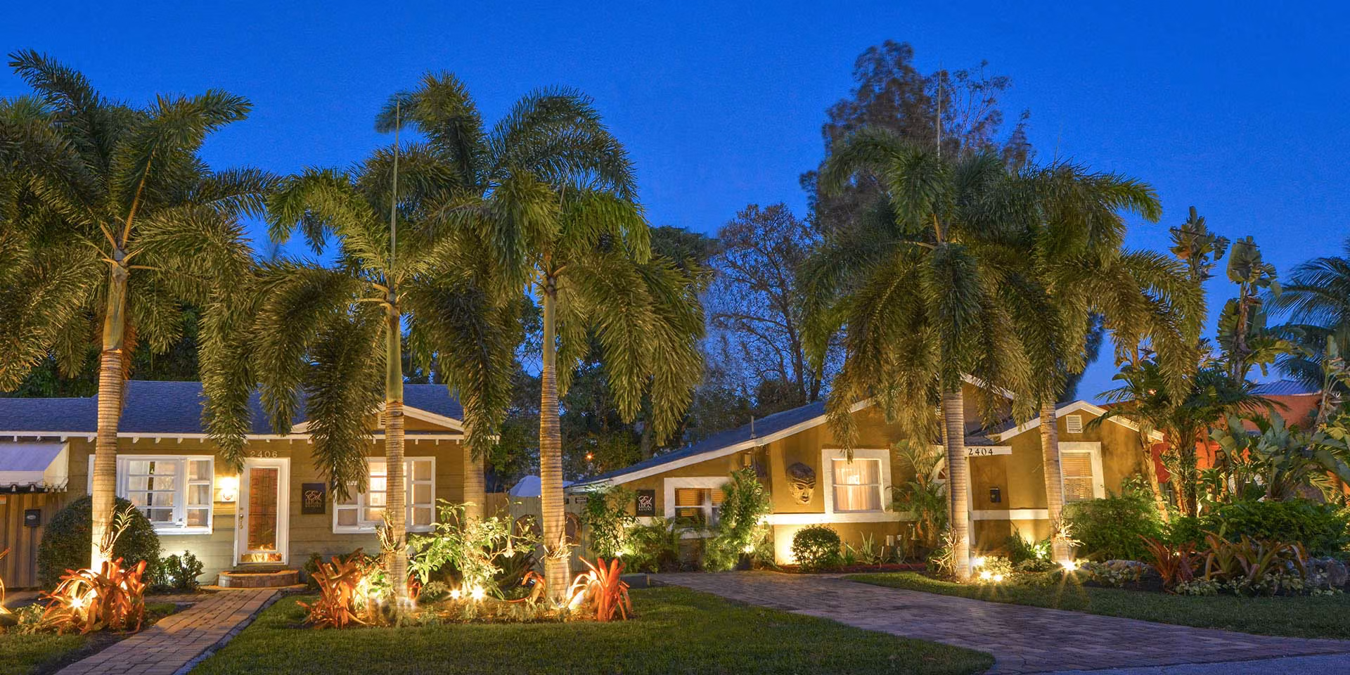 Palm trees and illuminated bungalow entrances at Ed Lugo Resort.