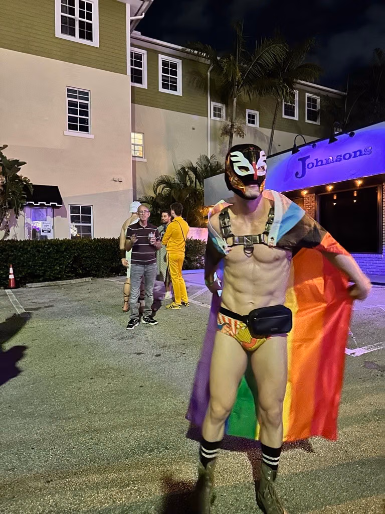 A masked festivalgoer in a rainbow cape outside Johnson’s on Halloween in 2023.