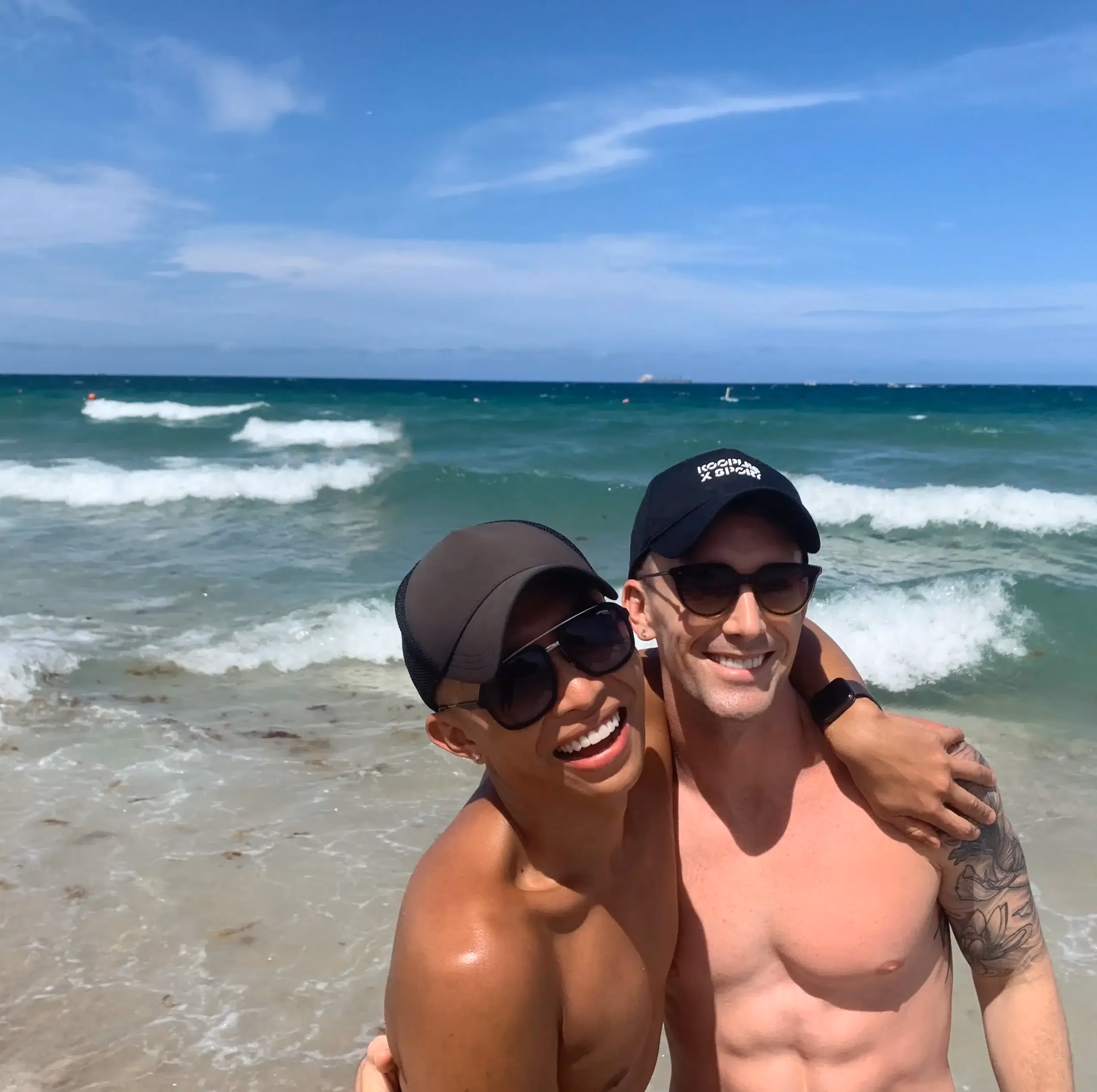 Two people standing together by the ocean