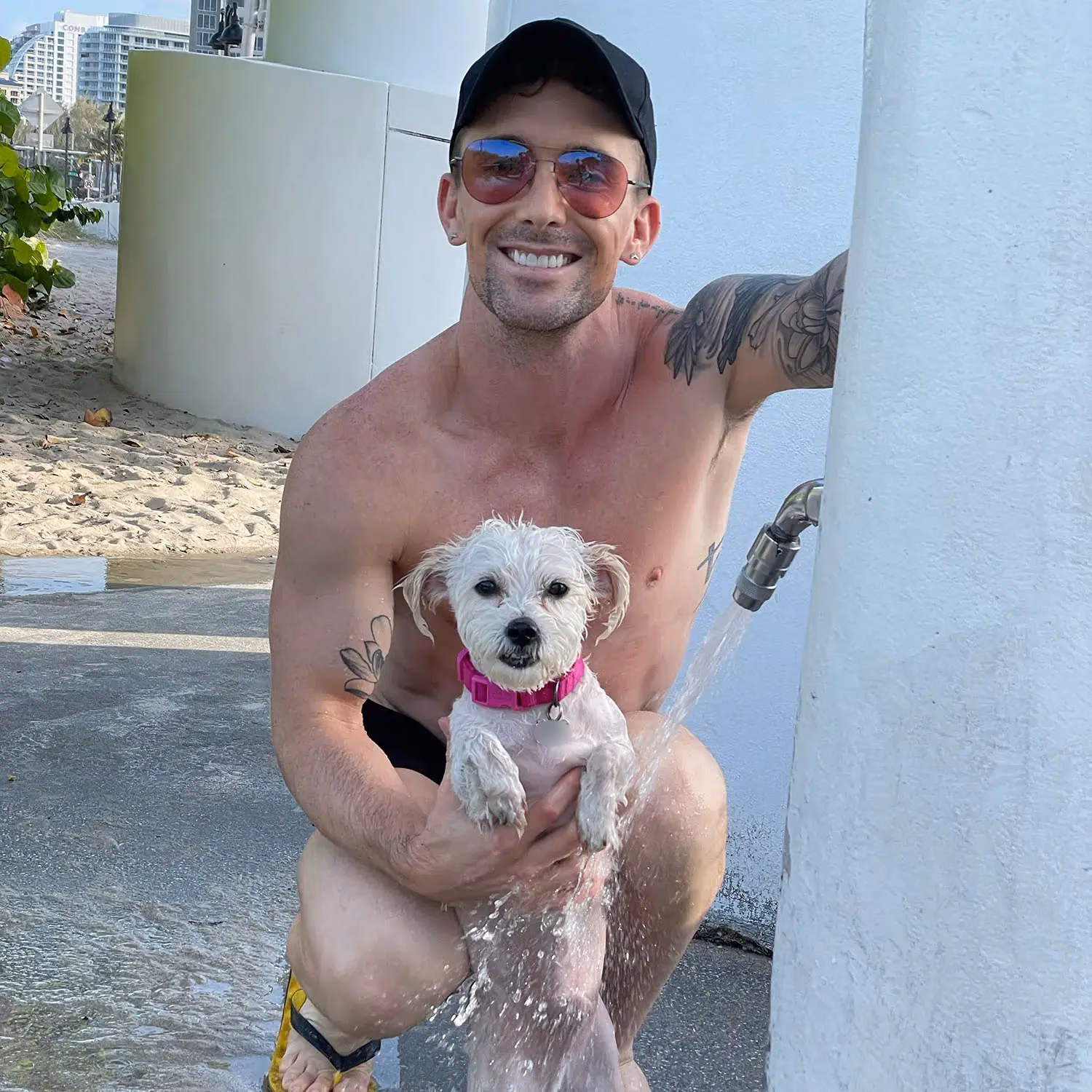 A person holding their dog beside an outdoor shower